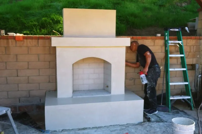 Mason applying finish coat to a custom outdoor fireplace and raised hearth