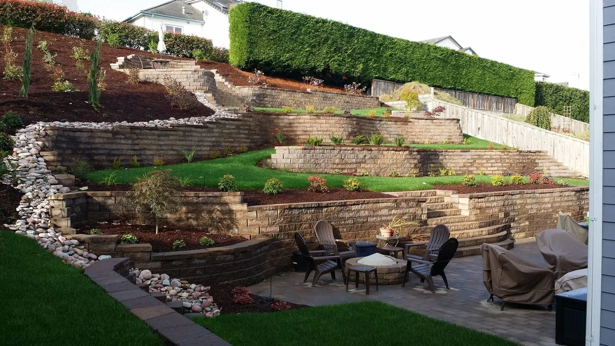 After - reinforced CMU retaining wall rebuilt on a new footing with grouted cells and drain rock behind the stem